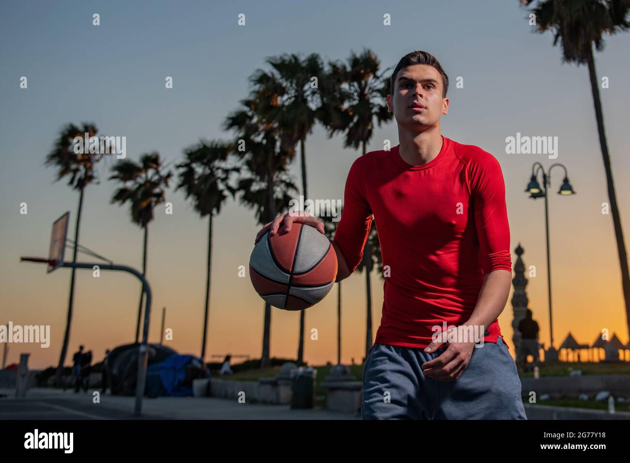 Basketball player shooting ball in hoop outdoor court. Urban youth game