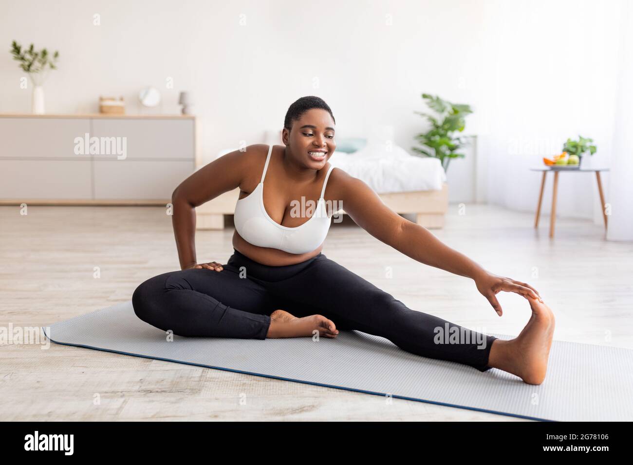 Curvy black lady stretching her legs, exercising on yoga mat, leading  active lifestyle, trying to lose weight at home Stock Photo - Alamy