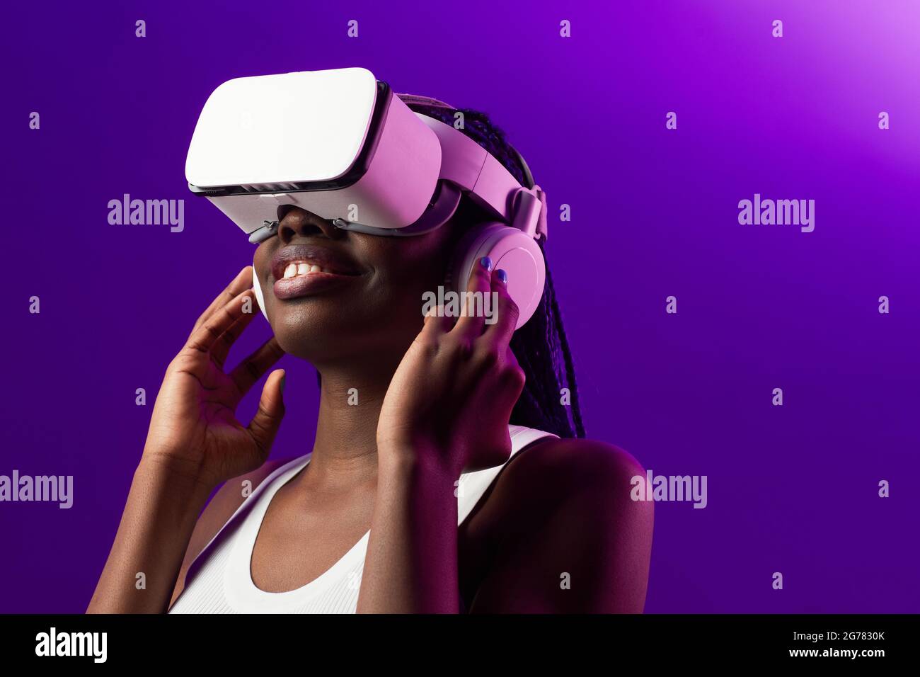 Futuristic portrait of young African-American woman wearing VR headset against purple background , copy space Stock Photo