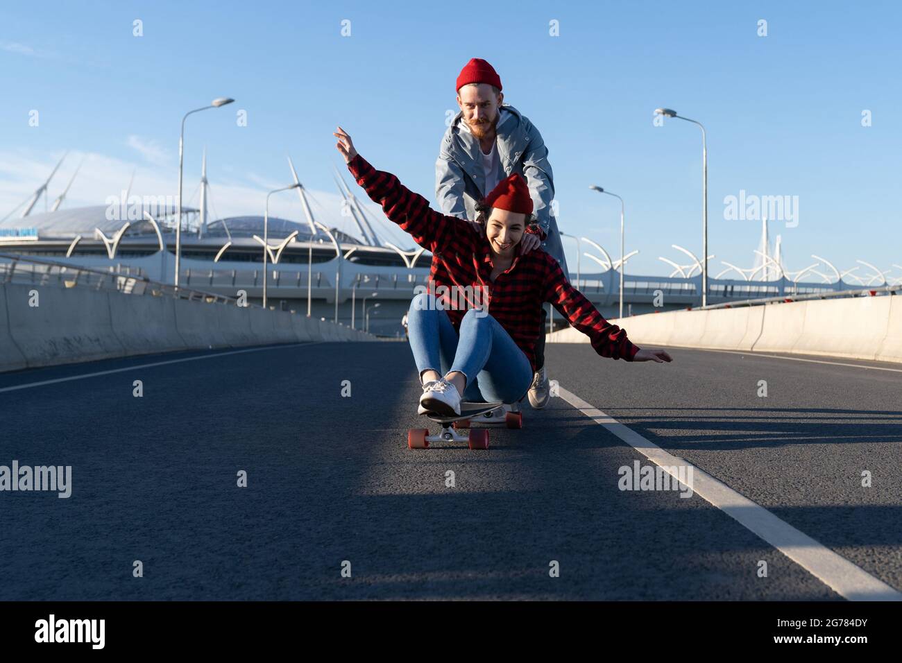 Carefree hipsters couple skateboarding together. Trendy man and woman enjoy time riding longboard Stock Photo