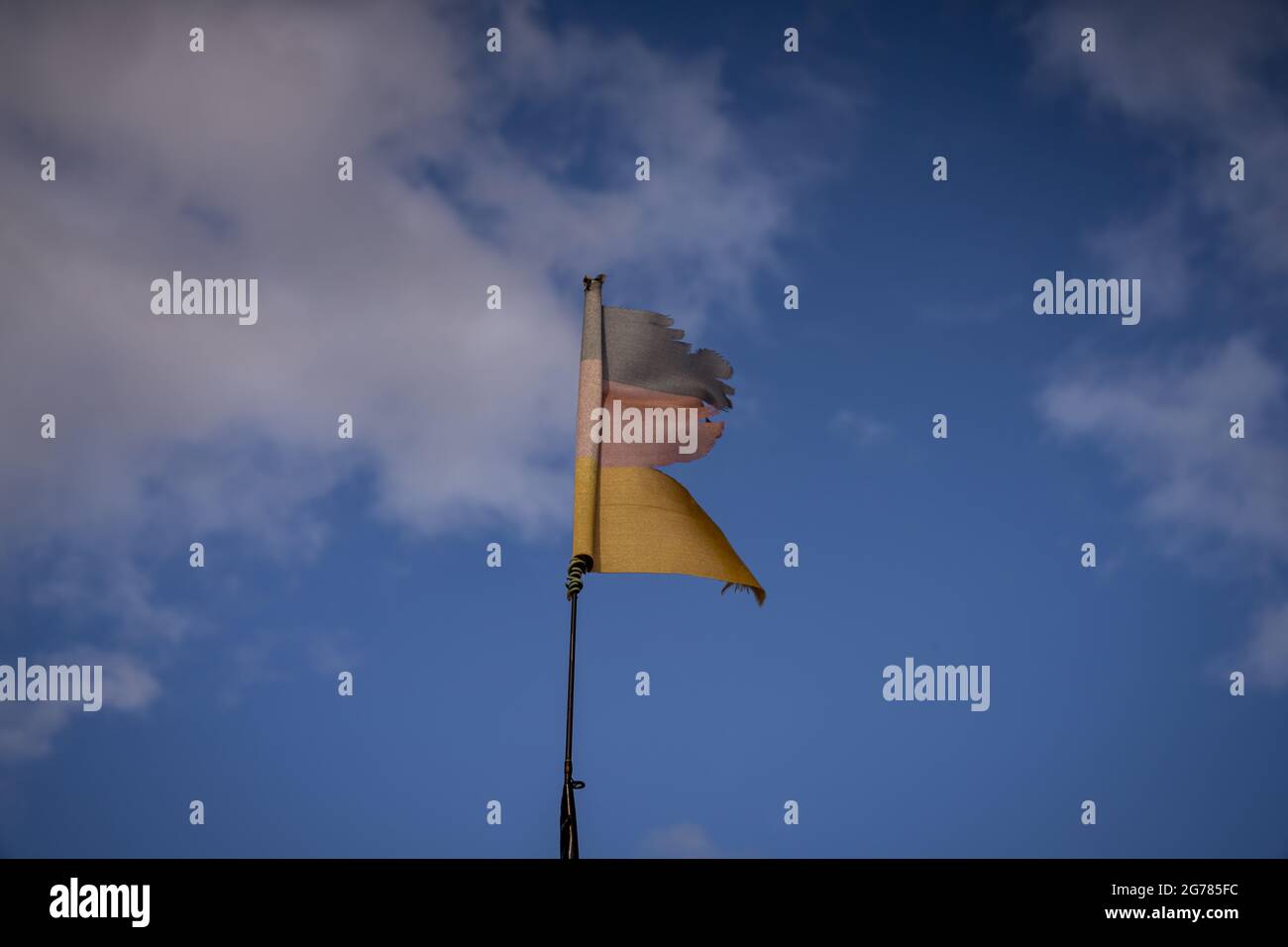 A torn German flag with clouds in the background, seen near Klein Kubitz, Mecklenburg-Western Pomerania, Germany Stock Photo