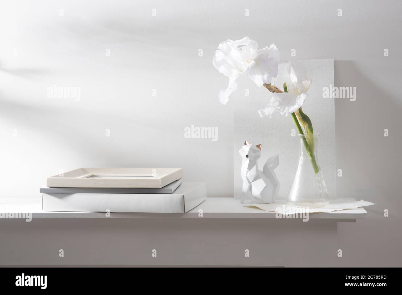 A vase with whiteiris, pieces of paper, a figurine with a fox. Scandinavian style. Stock Photo