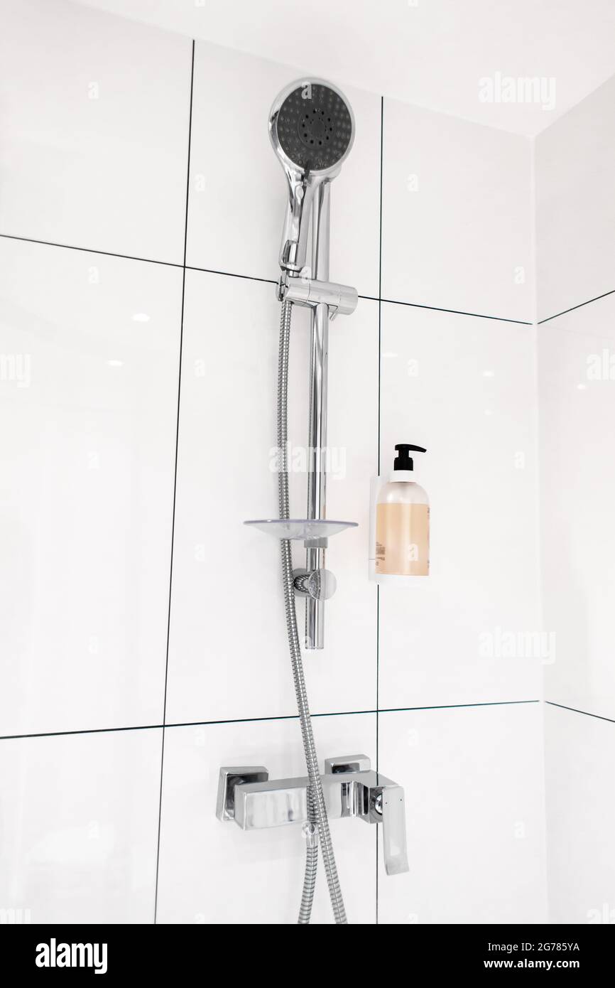 New black shower head on holder in white tiled bathroom in modern apartment  Stock Photo - Alamy