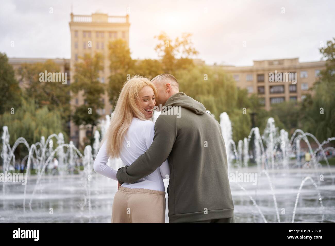 Couple in love walking outdoors park fountain Caucasian man woman walk outside after jogging dressed sport clothes  Healthy livestyle  Rear view Stock Photo