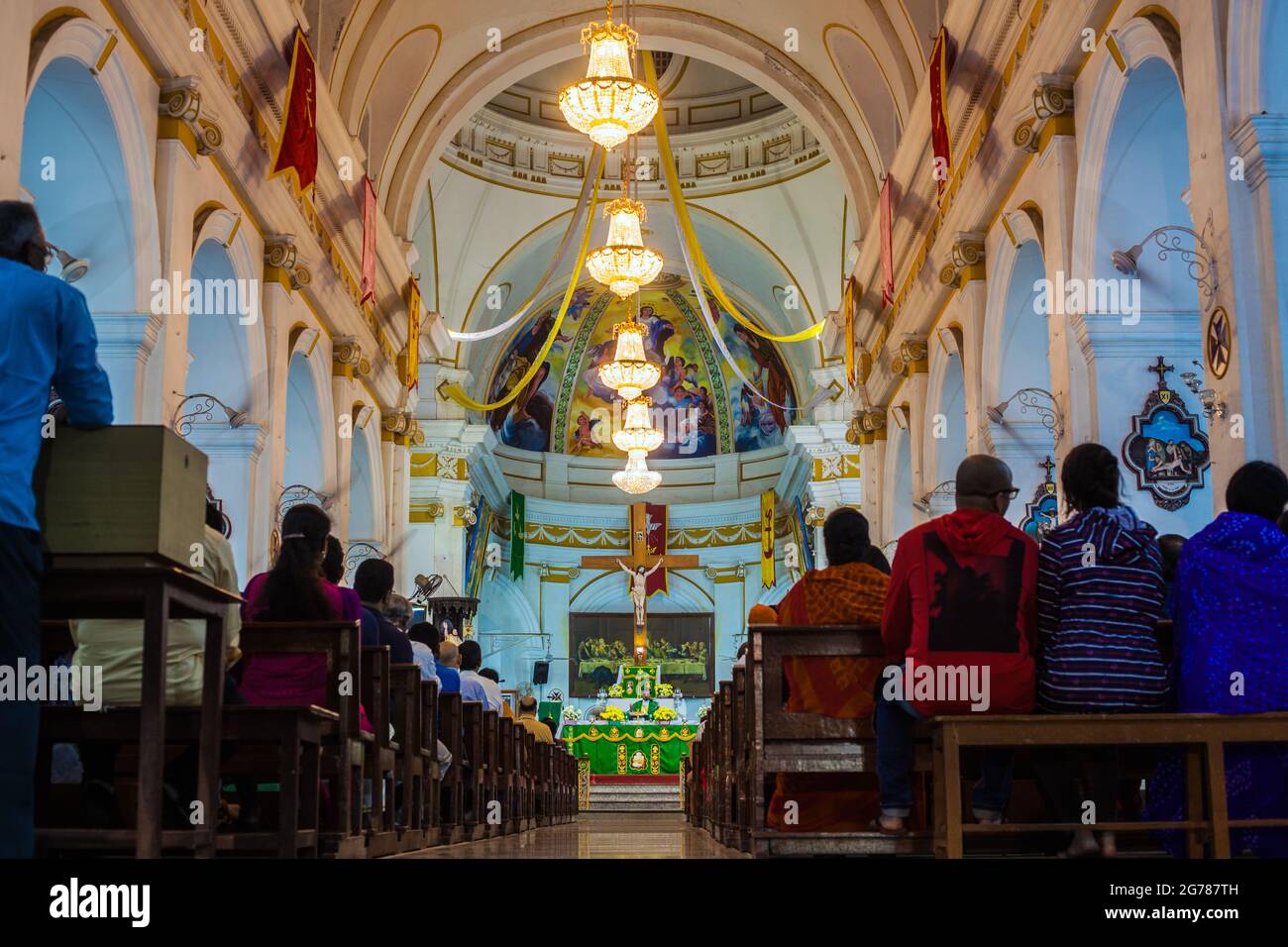 Bright chandeliers hanging from ornate ceiling over congregation at Immaculate Conception