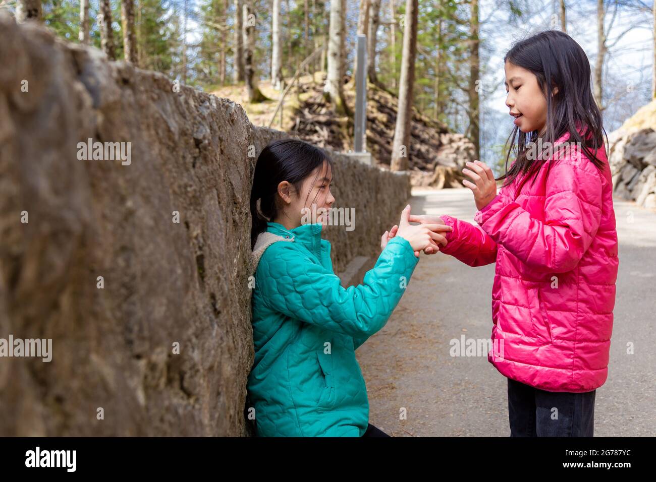 Playing Tack Two young Asian sisters playing hand clapping game, Tick Tack Toe an an ...
