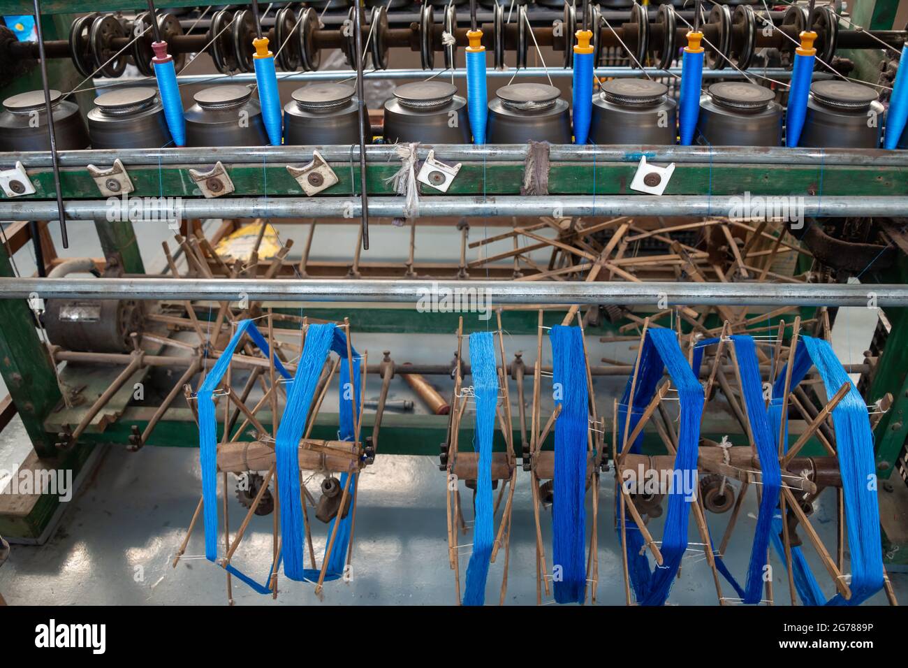 Skeins of blue silk being spooled on to bobbins for use in traditional weaving of cloth, Myanmar Stock Photo