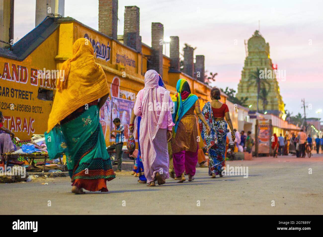 Indian females wearing colourful saris walking towards Sri Ramanathaswamy Temple after dusk, Rameshwaram, Tamil Nadu, India Stock Photo