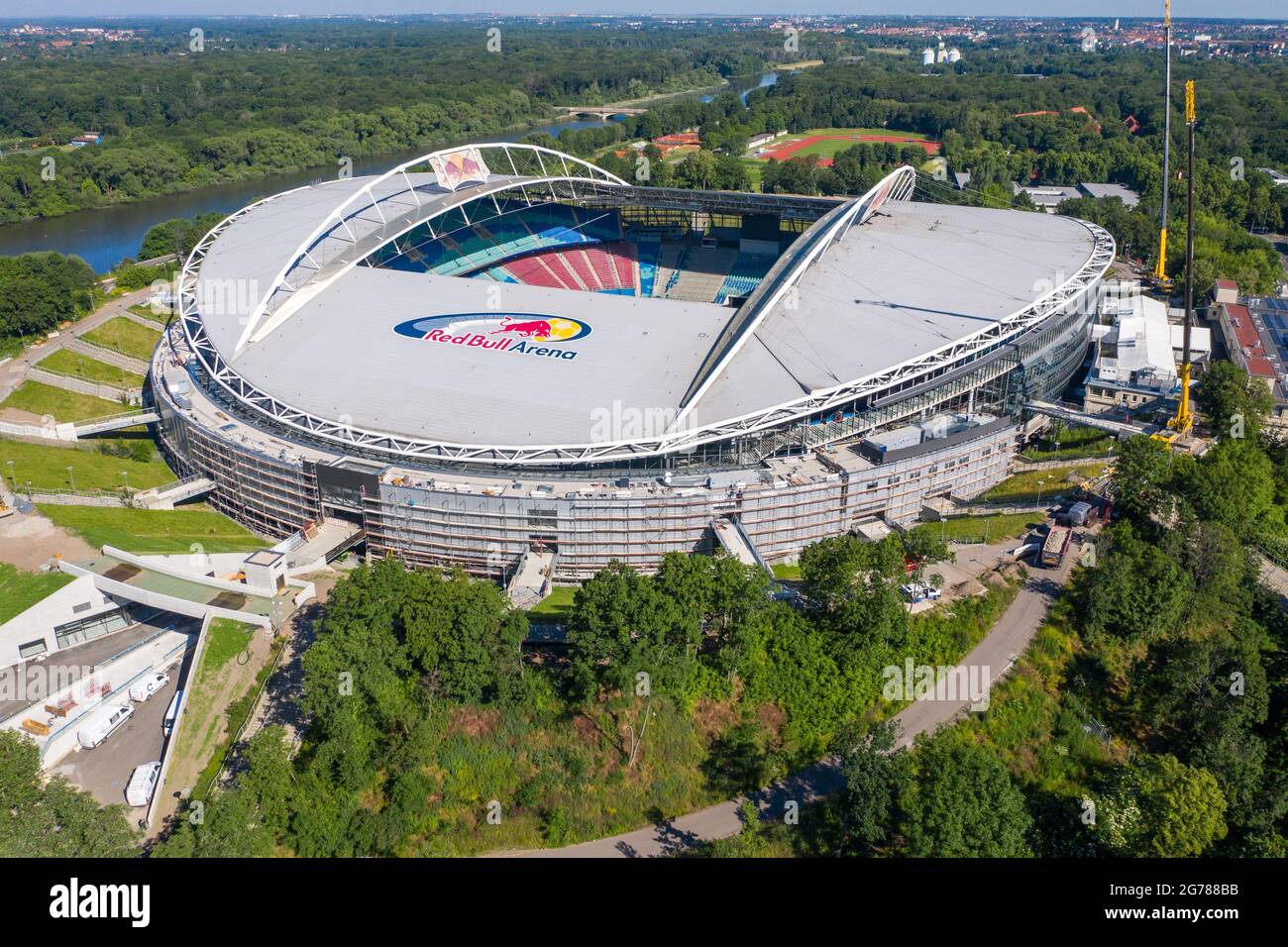 14 June 2021, Saxony, Leipzig: Two cranes stand at the Red Bull Arena. RB Leipzig's home ground is being rebuilt. The spectator capacity increases from 42,558 to 47,069 standing and seated. The outside of the stadium is enclosed with a soundproof facade. The embankment of the former Zentralstadion, which encompasses the arena, was cut open behind the historic bell tower to make room for a new entrance. RB Leipzig is investing a good 60 million euros in the conversion by 2022. (Aerial view with drone) Photo: Jan Woitas/dpa-Zentralbild/ZB - IMPORTANT NOTE: In accordance with the regulations of t Stock Photo