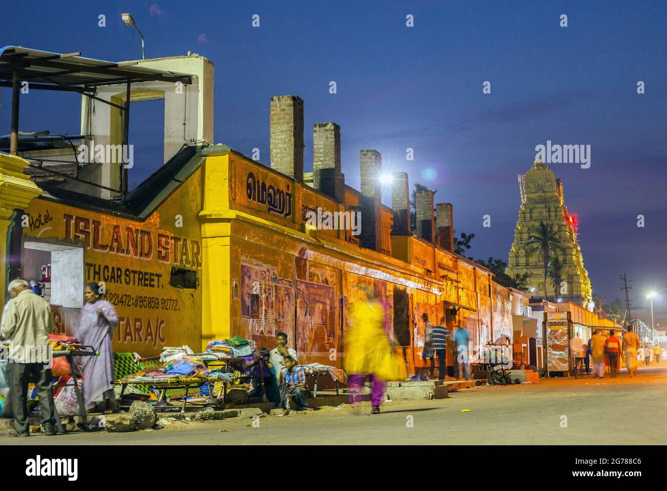 Clothing vendors set up in front of colourful building walls with Sri