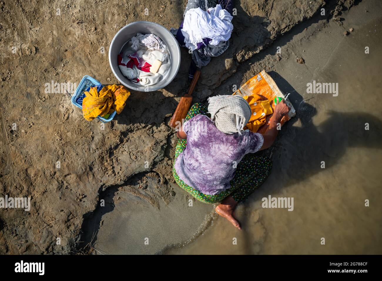 Woman hand washing clothing on a river bank, Sagaing, Myanmar. Aerial view  of woman wearing turban doing laundry on the banks of the Irrawaddy River Stock Photo