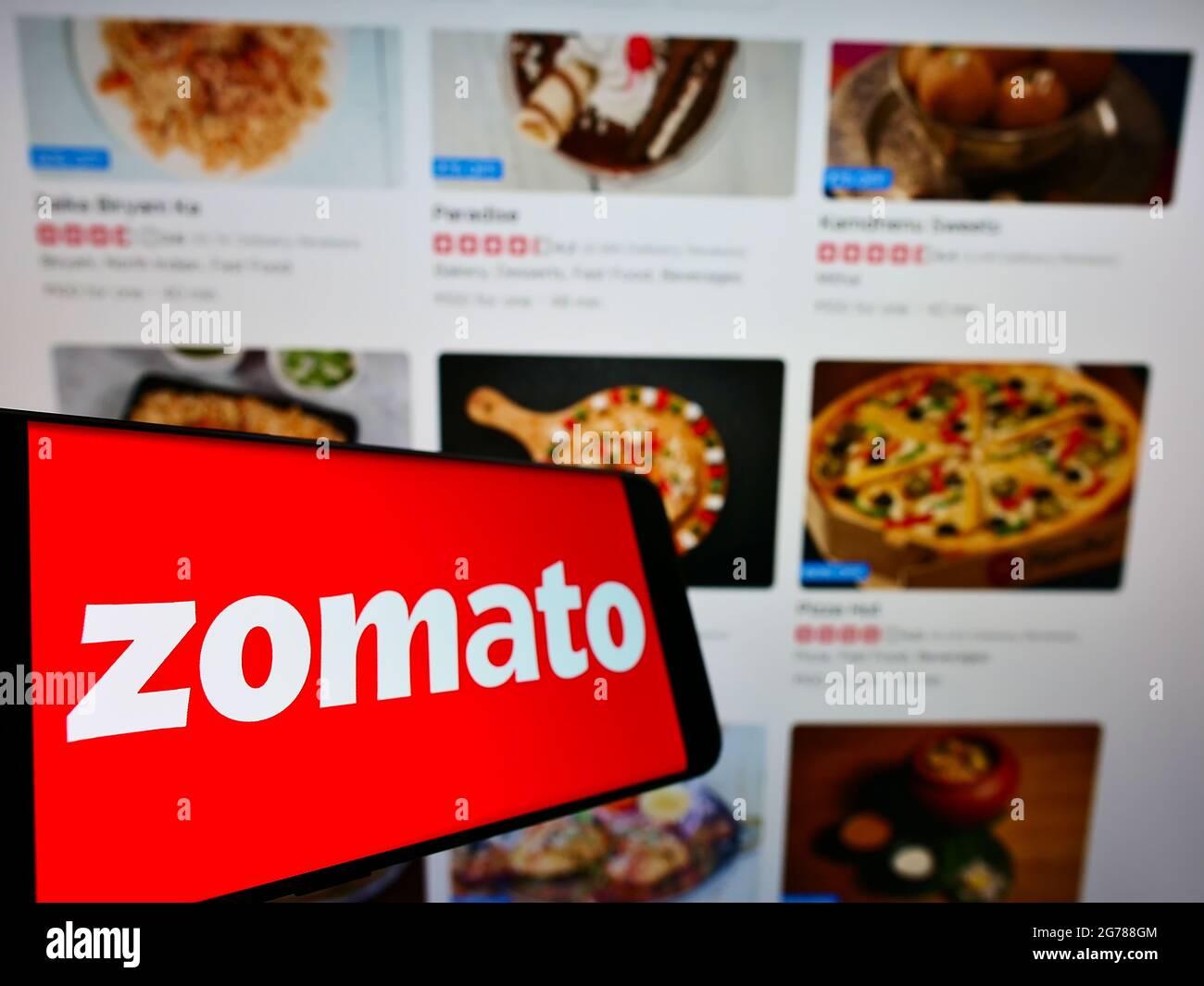 Smartphone with logo of Indian online food ordering company Zomato on screen in front of business website. Focus on center-left of phone display. Stock Photo