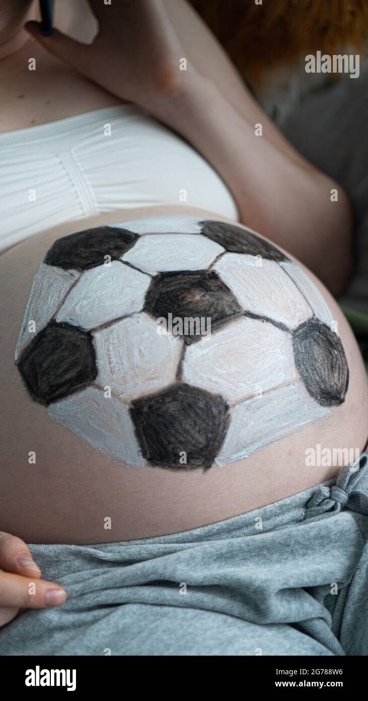 Conceptual image of pregnant female with painted soccerball on her belly Stock Photo