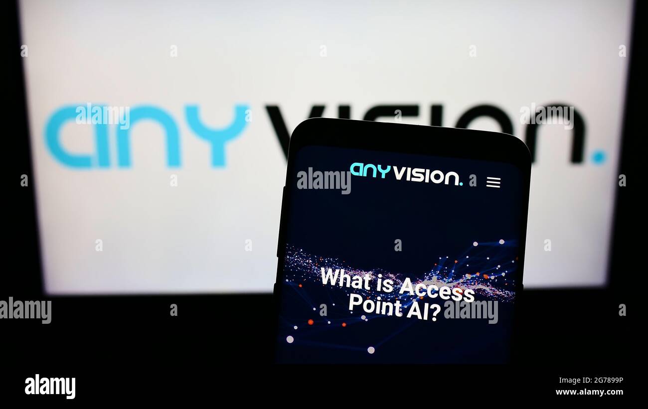 Mobile phone with webpage of company AnyVision Interactive Technologies Ltd. on screen in front of logo. Focus on top-left of phone display. Stock Photo