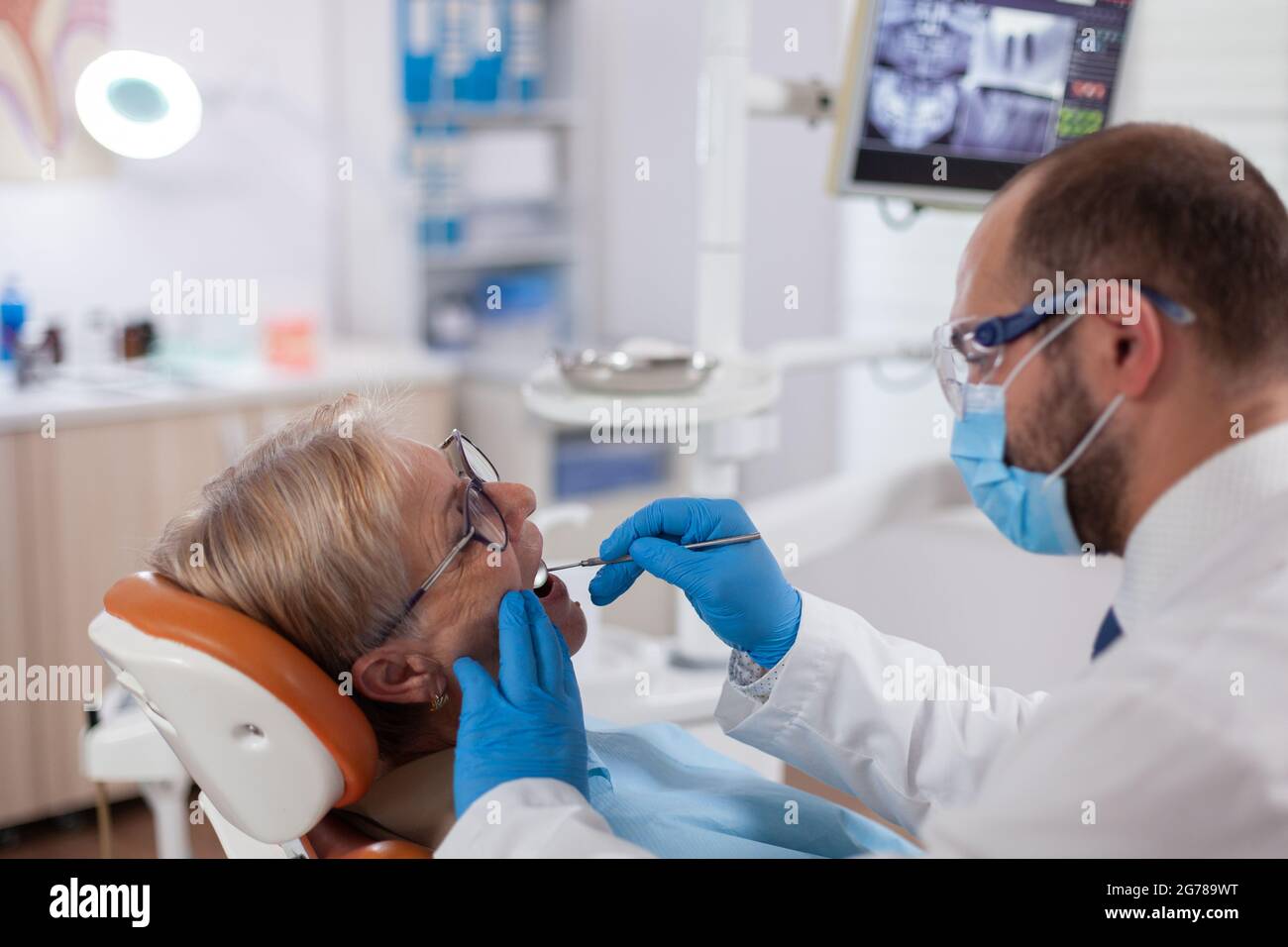 Stomatolog with senior client examining a patient teeth Elderly woman