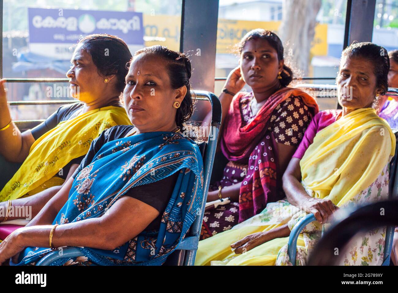 Four Indian female passengers wearing colourful saris travelling on the public bus, Kovalam, Kerala, India Stock Photo