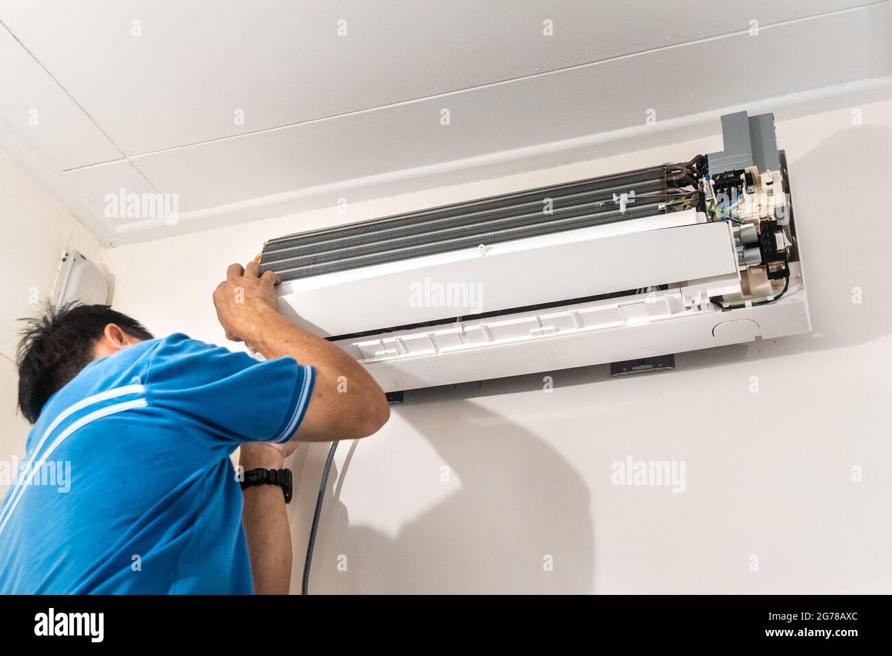 Technician installing indoor air conditioner condenser unit on wall