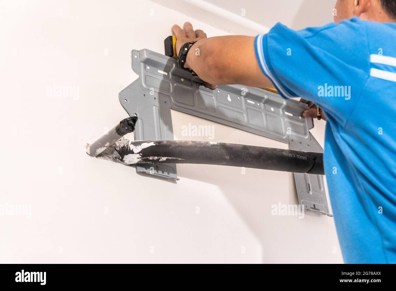 Technician installing wall bracket of air conditioning condenser unit