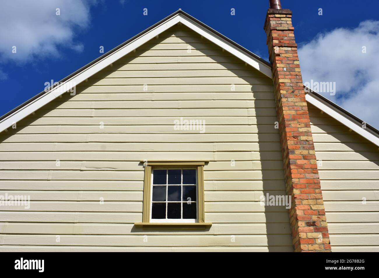 Wall detail of vintage wooden house with red brick chimney and gable roof. Stock Photo