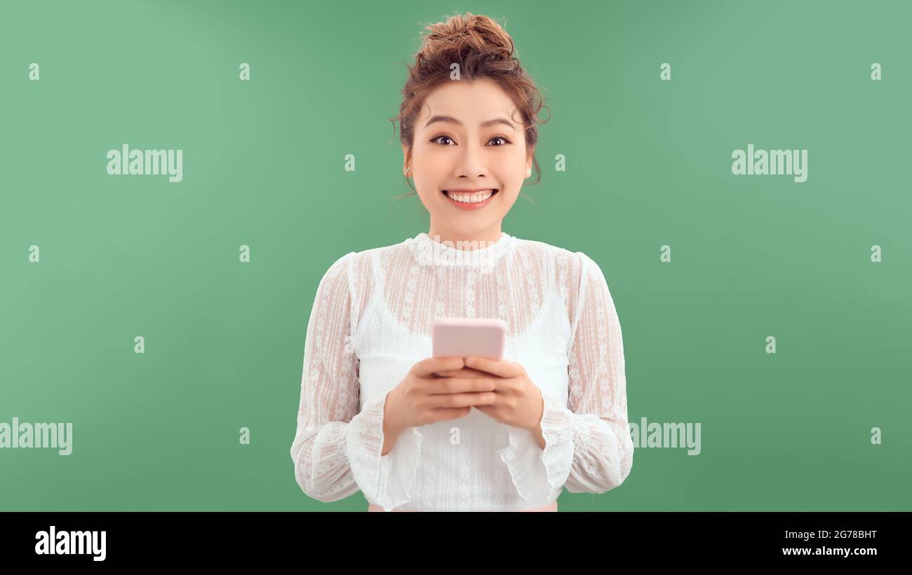 Attractive asian girl using mobile phone, texting, messaging or chatting with friends online, starting to laugh Stock Photo