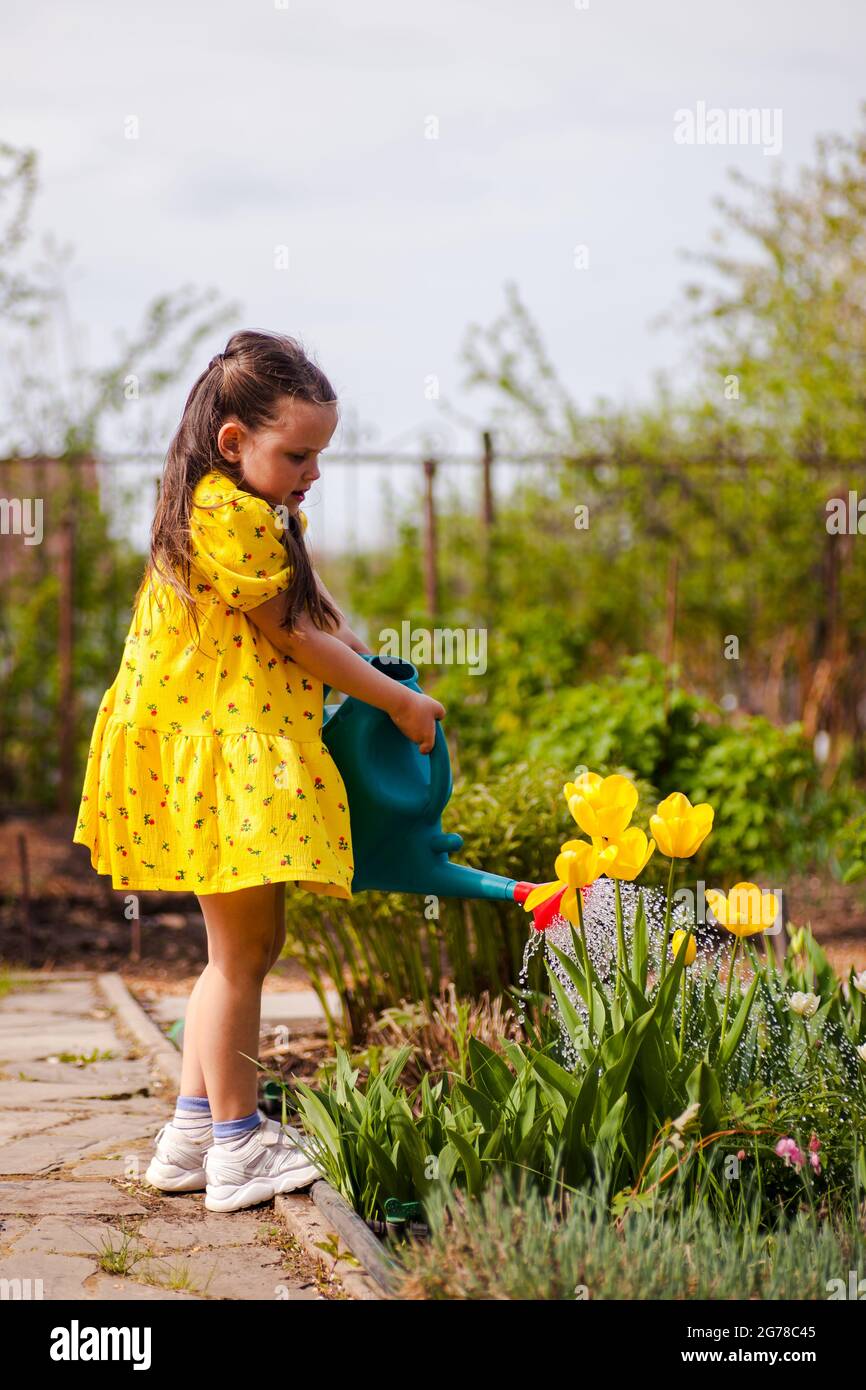 fulllength portrait of a girl watering flowers from a garden watering