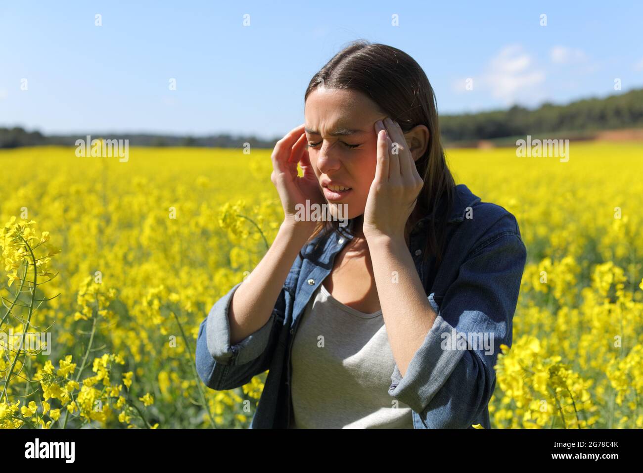 Stressed woman suffering head ache in a yellow field on summer Stock Photo