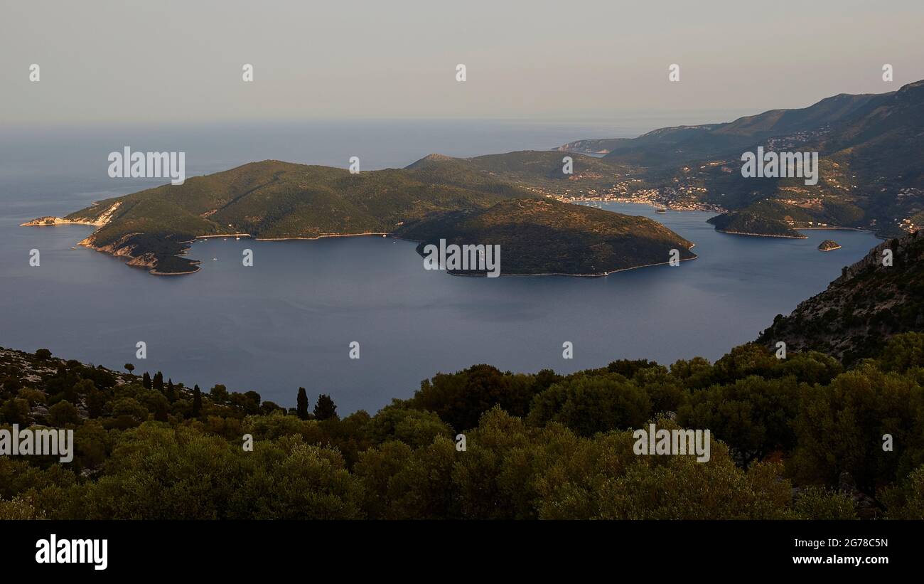 Ionian Islands, Ithaka, island of Odysseus, capital, Vathi, view from above of the Molos Bay, green hills in the foreground, the bay of Vathi in the top right in the picture, green hills all around, blue sea, sky light blue to white Stock Photo