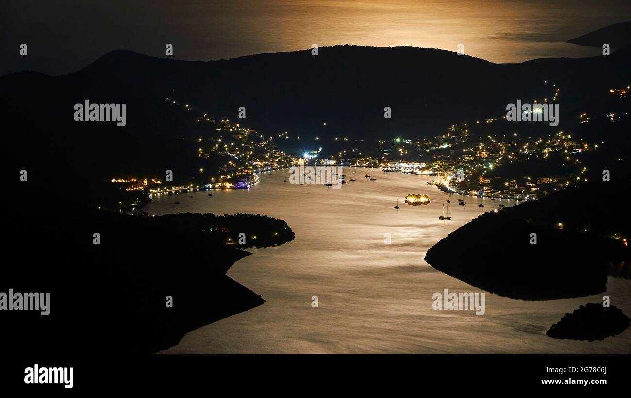 Ionian Islands, Ithaca, island of Ulysses, full moon, bay of Vathi, night shot, moon shimmer on the sea, Vathi at night, boats in the bay, hill behind Vathi Stock Photo