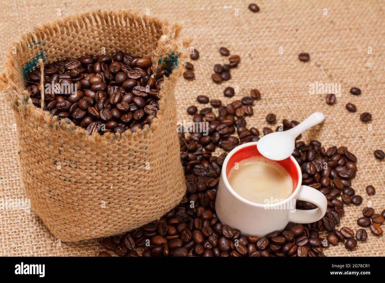 Roasted coffee beans in a canvas sack and cup of coffee. Stock Photo