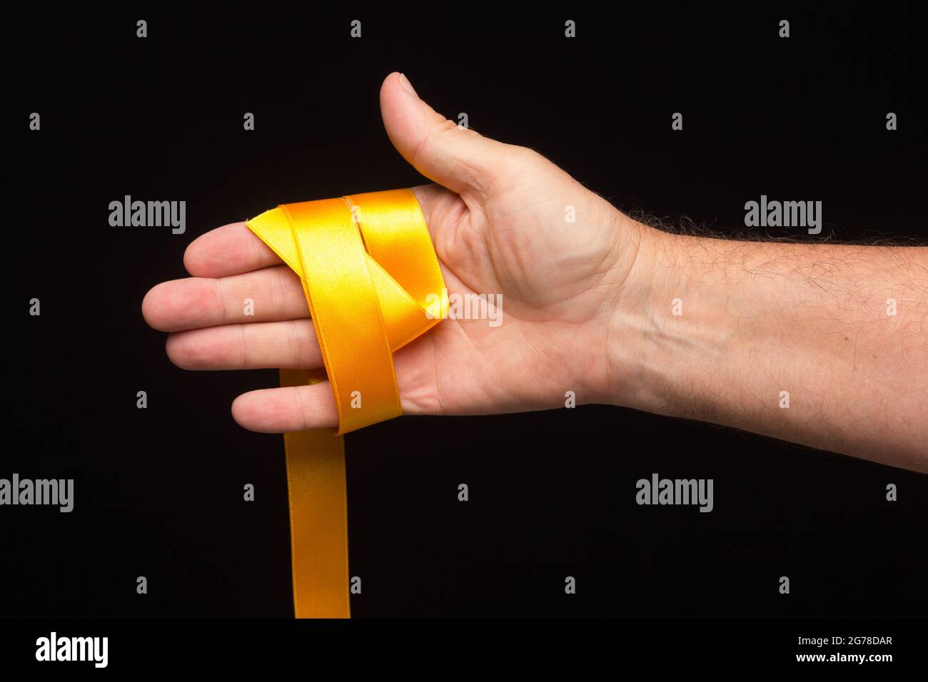 yellow ribbon in the palm of the hand on a black background; preparing ...