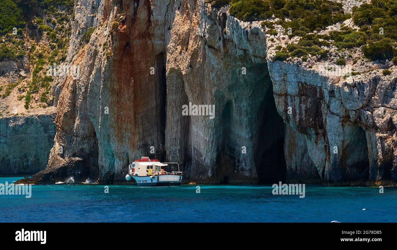 Ionian Islands, Zakynthos, northeast coast, Blue Caves, Blue Grottoes, morning light, rocky coast, small excursion boat is at anchor Stock Photo