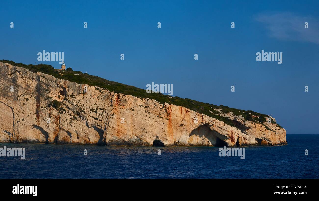 Ionian Islands, Zakynthos, northeast coast, Blue Caves, Blue Grottoes, morning light, sea in the lower third, dark blue, grottoes above, lighthouse on rocky coast, blue sky Stock Photo