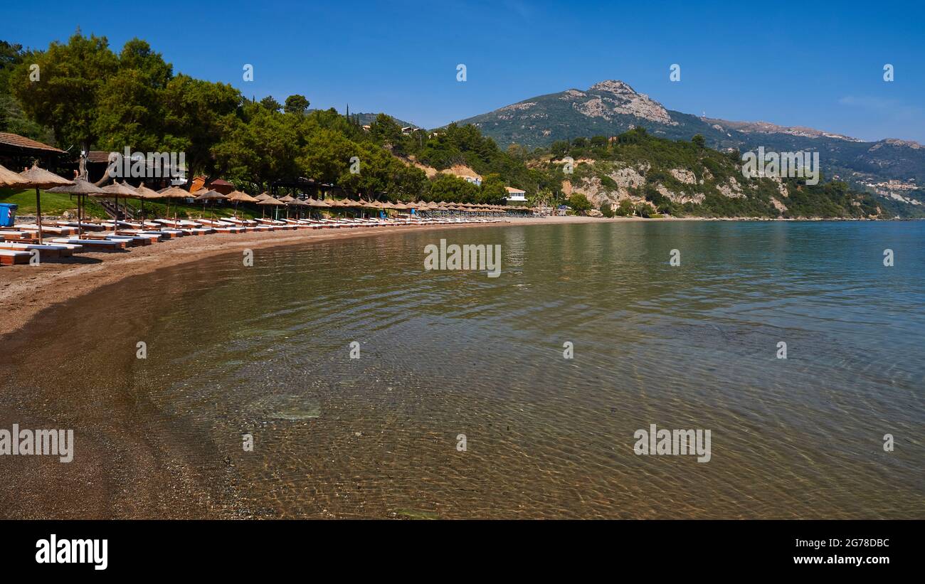 Ionian Islands, Zakynthos, south of Zakynthos Town, Banana Beach, semicircular bay, sandy beach, lined up sun loungers with umbrellas, sea green-blue, sky blue, mountain in the background Stock Photo