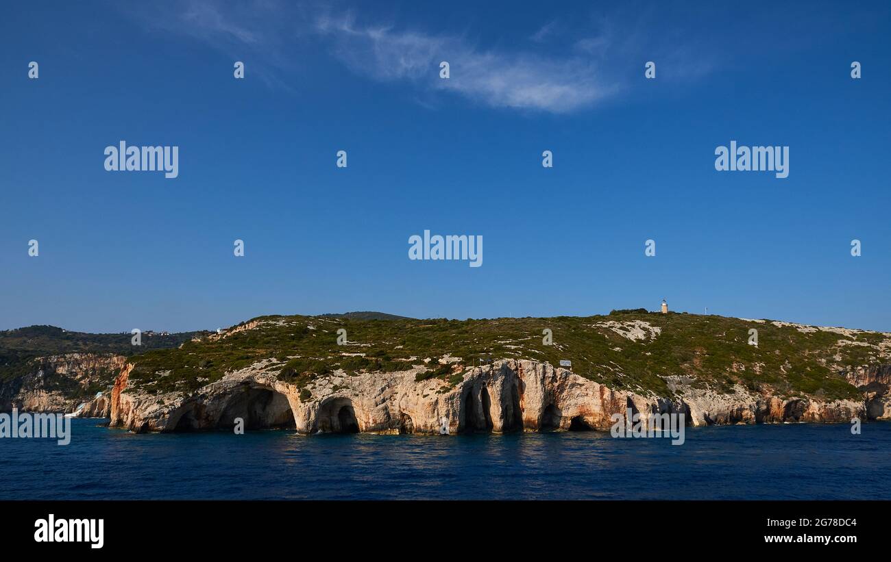 Ionian Islands, Zakynthos, northeast coast, Blue Caves, Blue Grottoes, morning light, panoramic view of the grottoes from the front, many rock arches and cave entrances can be seen, the sea in the lower quarter of the image is dark, the blue sky over the grottos with a veil takes more than half of the image Stock Photo