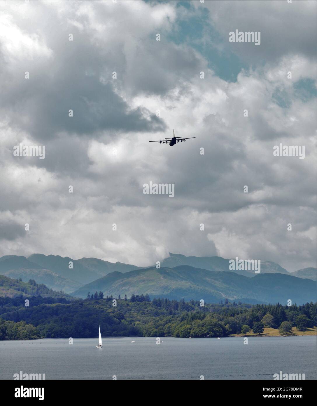 Stormy Weather Ahead. Yacht on Windermere and military transport aircraft head into stormy weather. Stock Photo