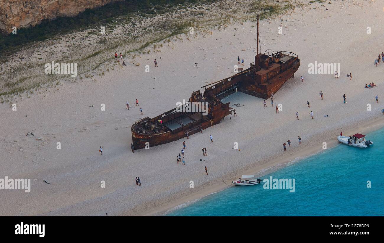 Zakynthos, Paralia Navagio, Shipwreck Beach, view from above of the shipwreck of the MV Panagiotis lying on the beach, people in the sky around the wreck, telephoto, bottom right triangle with green-blue sea, excursion boats at anchor on the beach Stock Photo