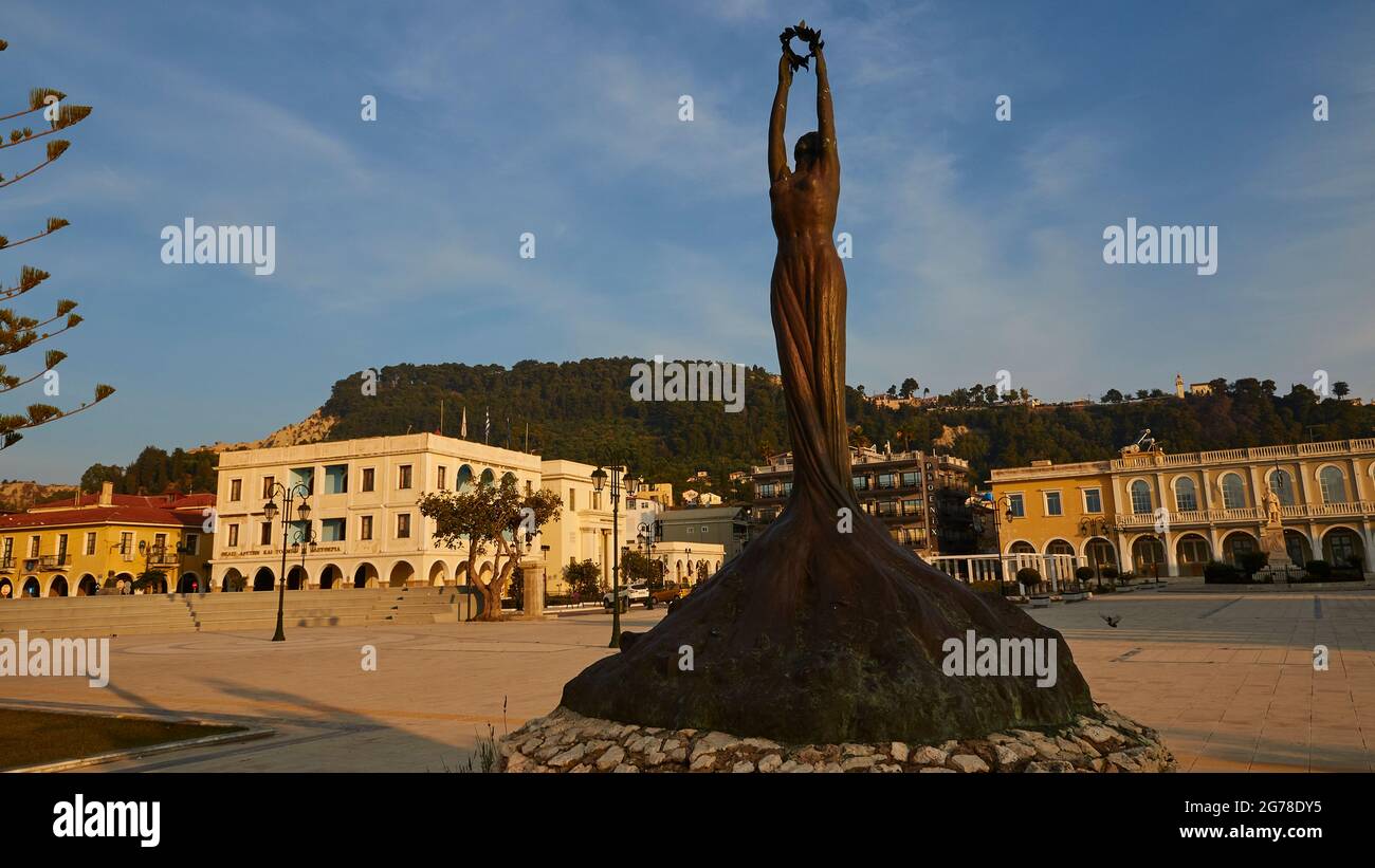 Zakynthos, Zakynthos Town, Solomos Square, morning light, bronze statue of liberty, wide angle view, statue and plinth on the right in the picture, Solomos Square with buildings in the background, white clouds in the blue sky Stock Photo
