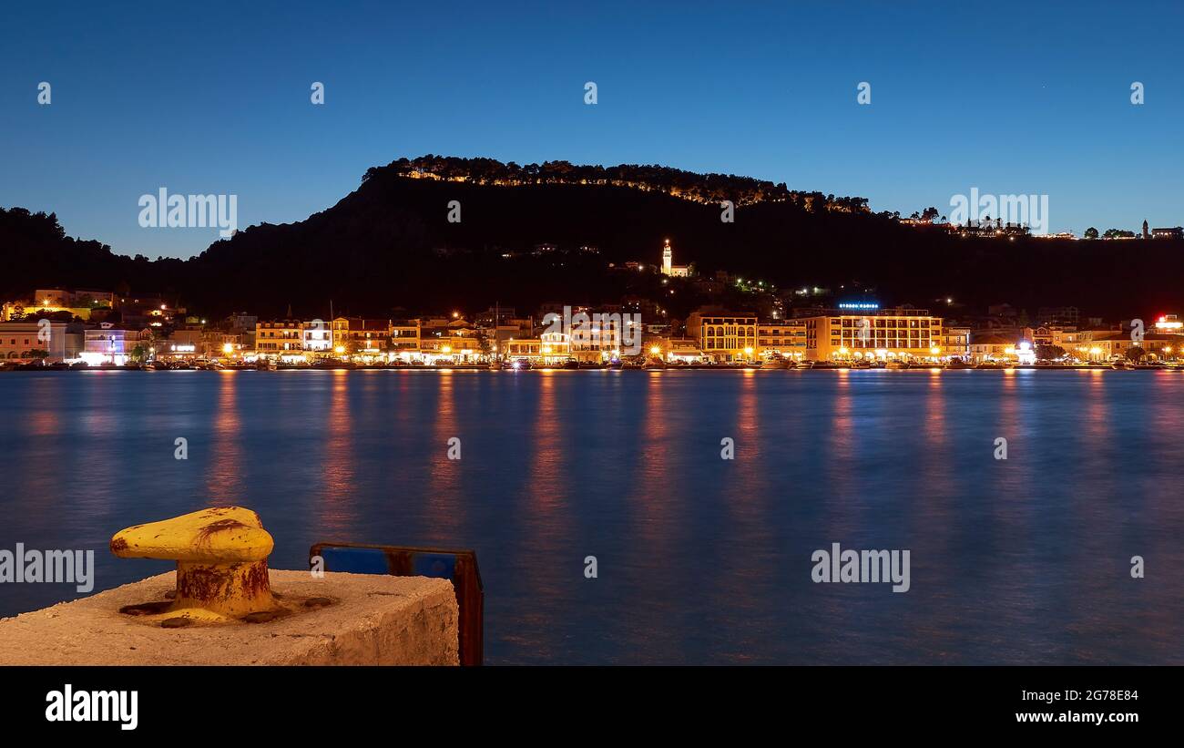 Zakynthos, Zakynthos City, night shot, evening shot, harbor, jetty yellow in the foreground, night skyline of Zakynthos city in the middle distance, castle hill in the background, blue night sky, light reflections on the water Stock Photo