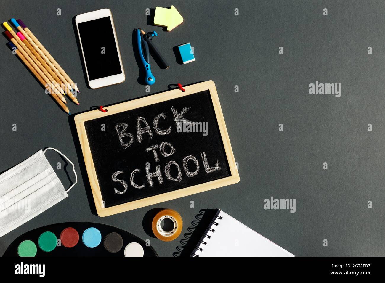 E- learning,Online education, School stationery supplies, medical mask, social distancing, school reopening. Back to school after covid-19 pandemic. New normal concept.Top view copy space,blackboard. Stock Photo