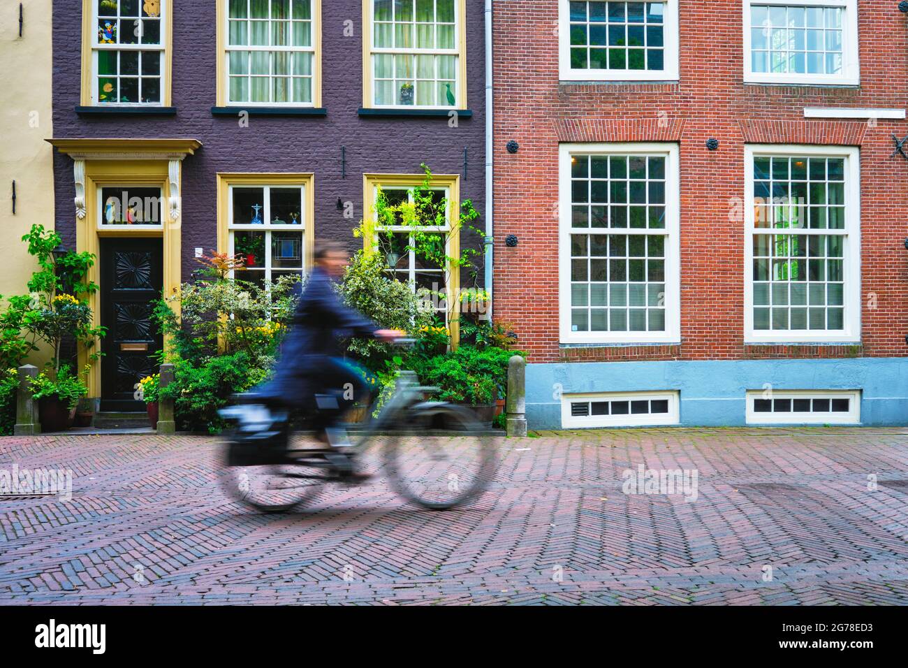 Bicycle rider cyclist man on bicycle very popular means of transoirt in Netherlands in street of Delft, Netherlands Stock Photo
