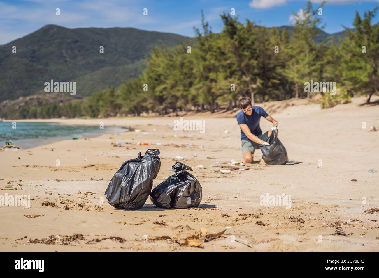 Man in gloves pick up plastic bags that pollute sea. Problem of spilled