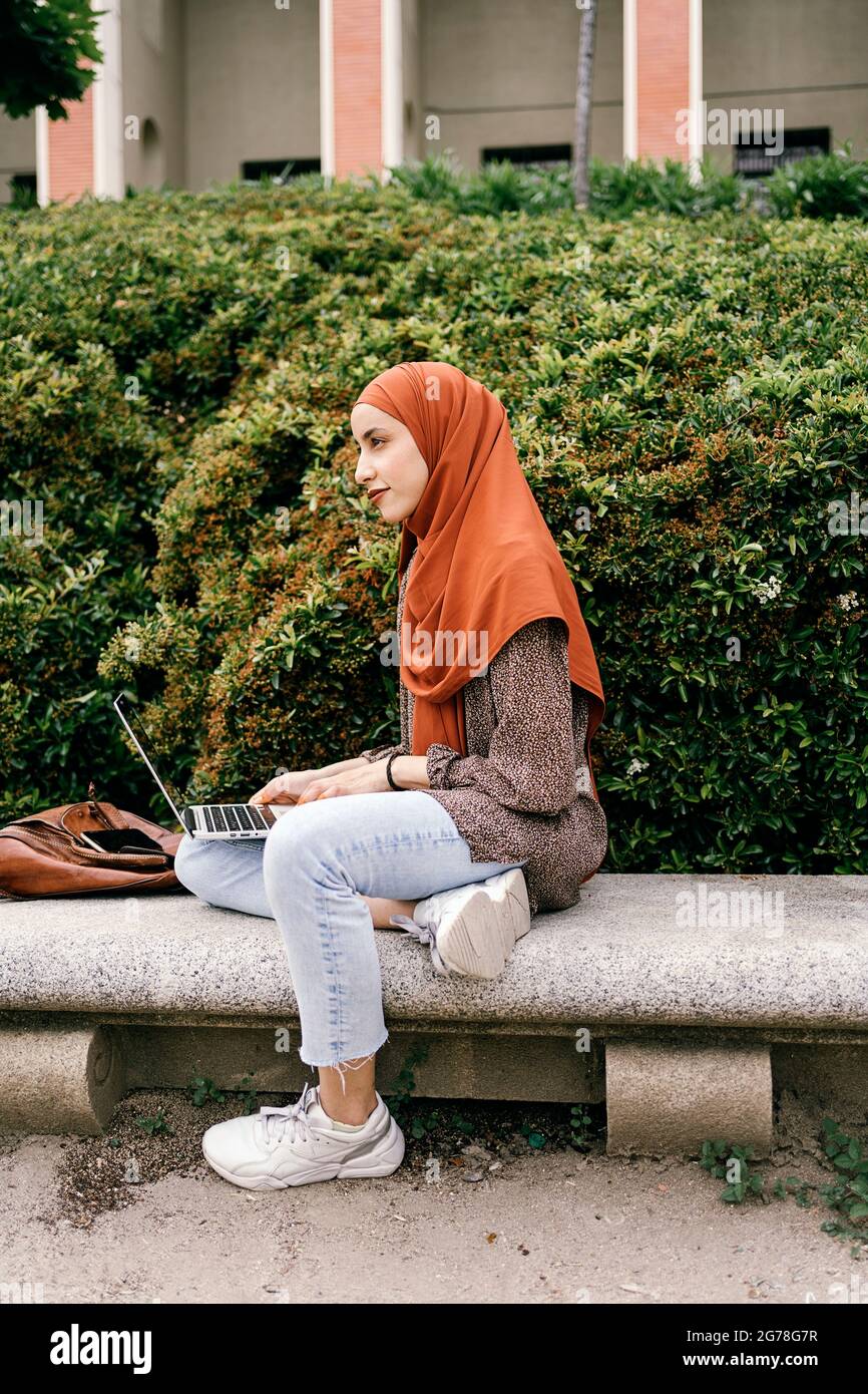 Beautiful young muslim woman wearing hijab sitting in the park and ...