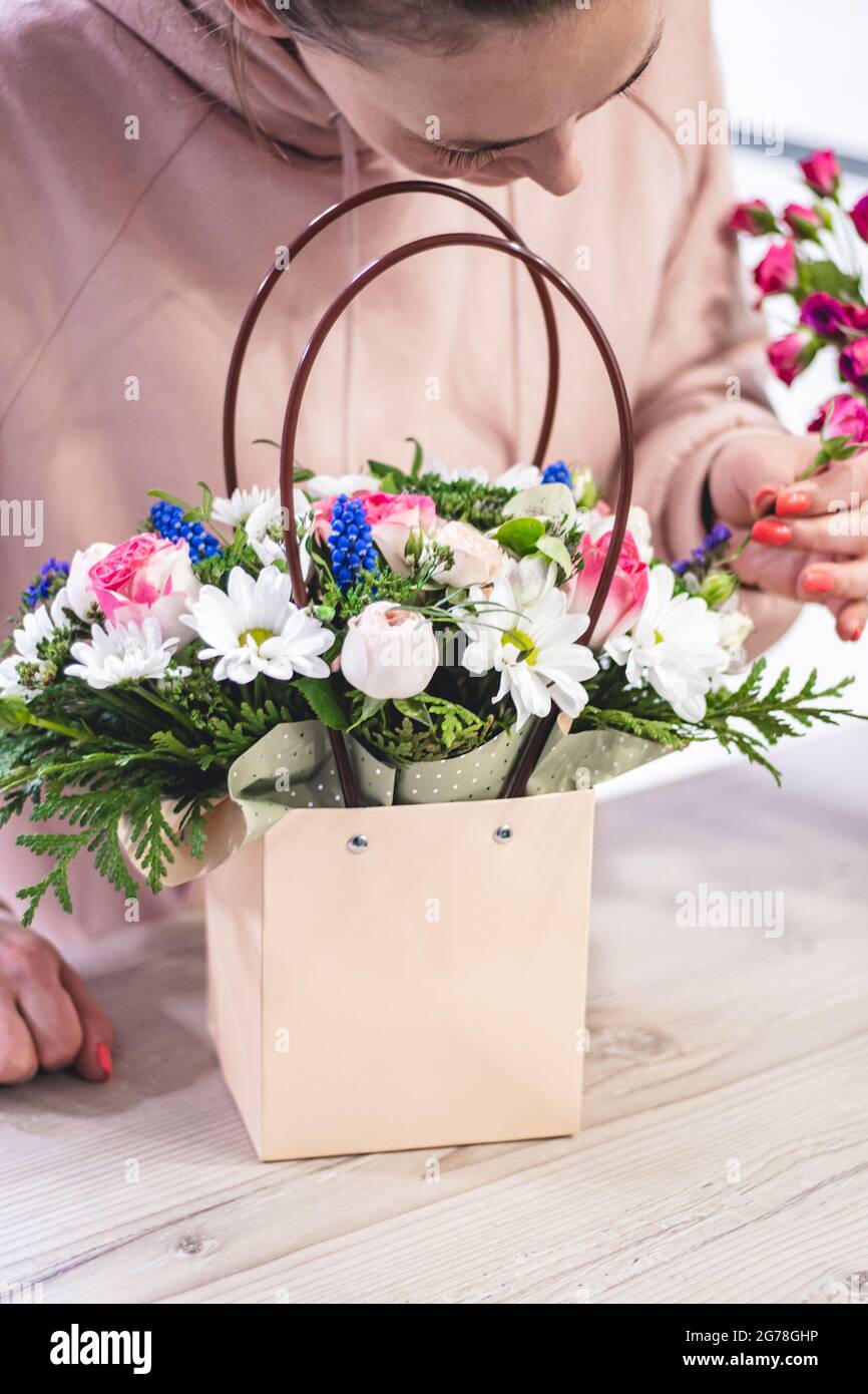 Female picking up bouquet of different flowers in paper gift bag with  handles, vertical Stock Photo - Alamy