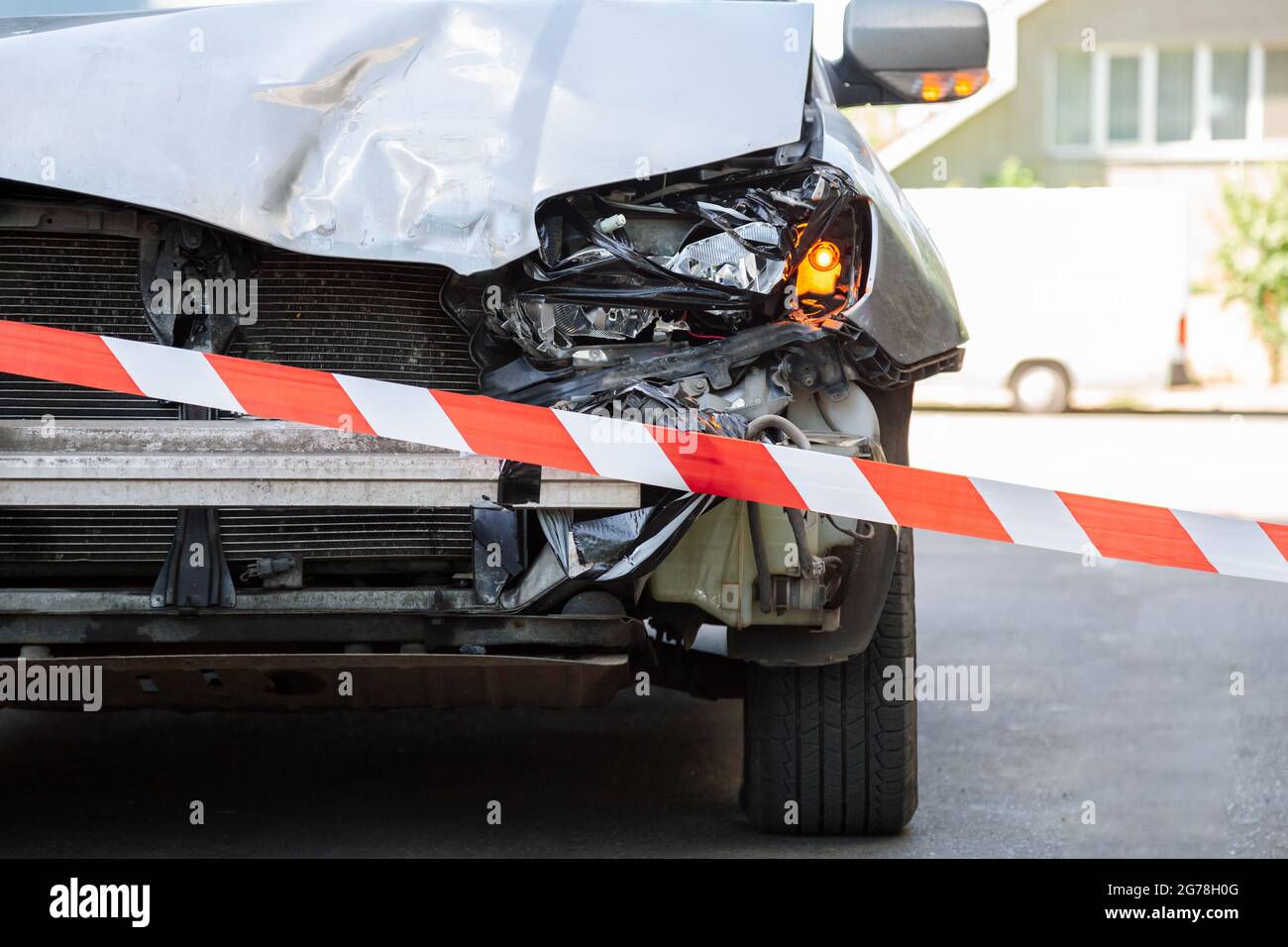 Crossed red white warning tape in front of destroed car accident. Broken hood of car on road fenced by Red warning tape. Broken Bumper and Car Stock Photo