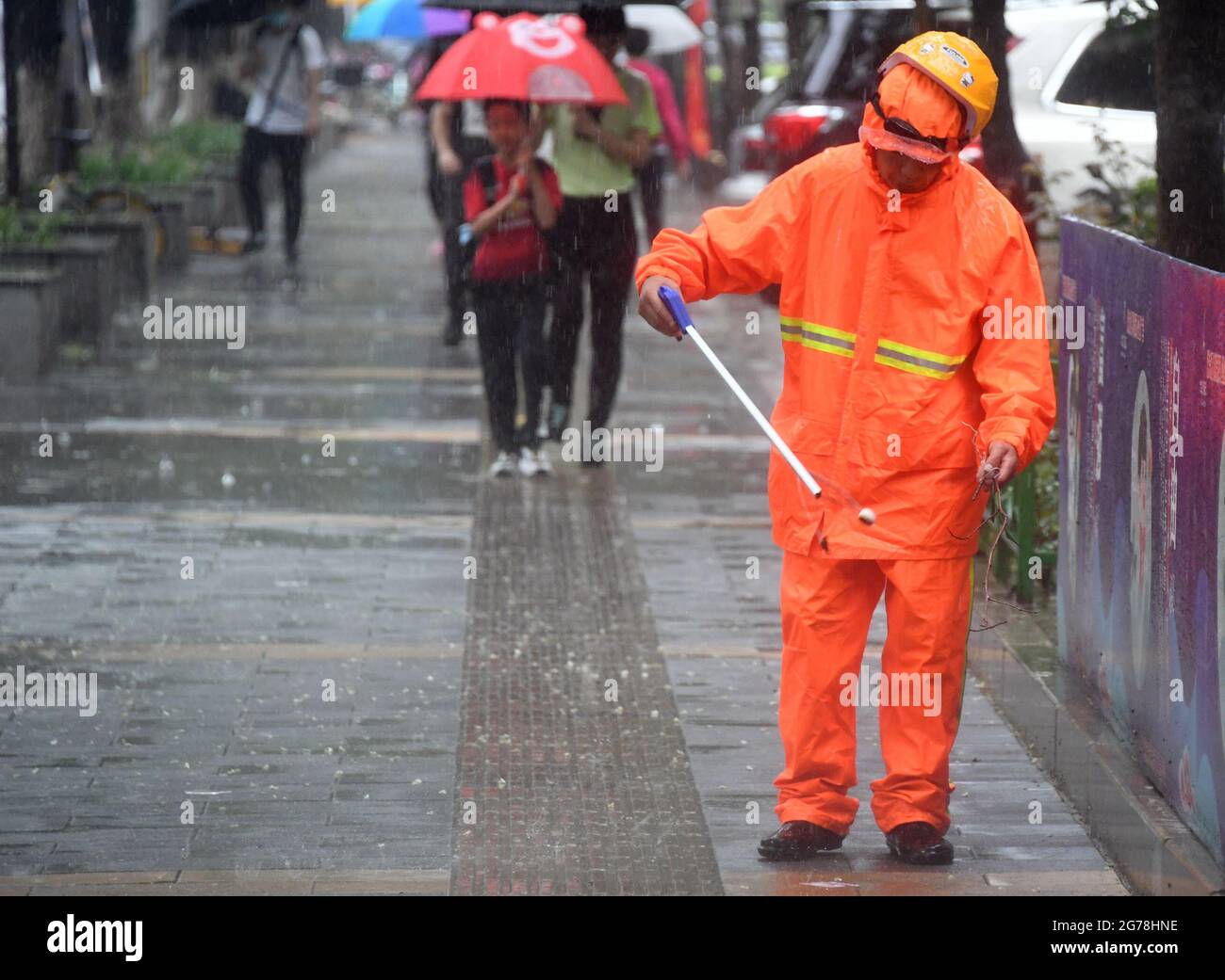 Beijing, China. 12th July, 2021. A cleaner works in rain on a street in Haidian District of Beijing, capital of China, July 12, 2021. Heavy rainstorm has lashed the Chinese capital Beijing since 6 p.m. Sunday with precipitation up to 116.4 mm, according to the municipal flood control department. From 6 p.m. Sunday to 9 a.m. Monday, Beijing registered average rainfall of 65.9 mm. Urban areas of the city reported higher average precipitation of 79.9 mm. Credit: Ren Chao/Xinhua/Alamy Live News Stock Photo
