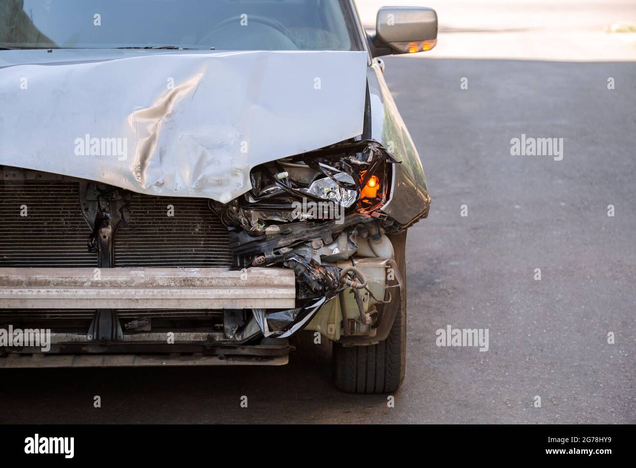 Crumpled car stands on road with Broken hood after car accident with