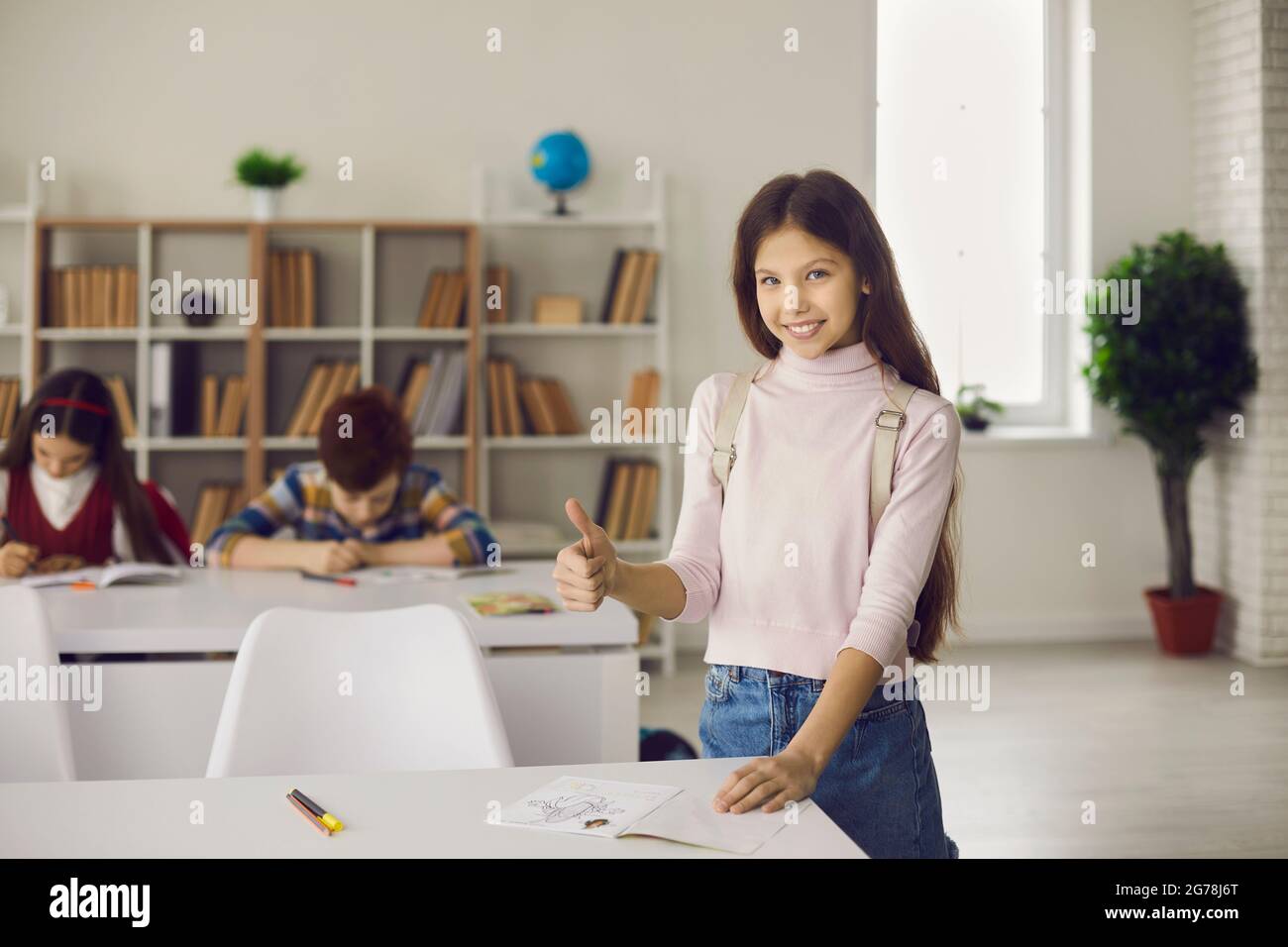 Schoolgirl showing thumbs up approve and recommend elementary school education Stock Photo