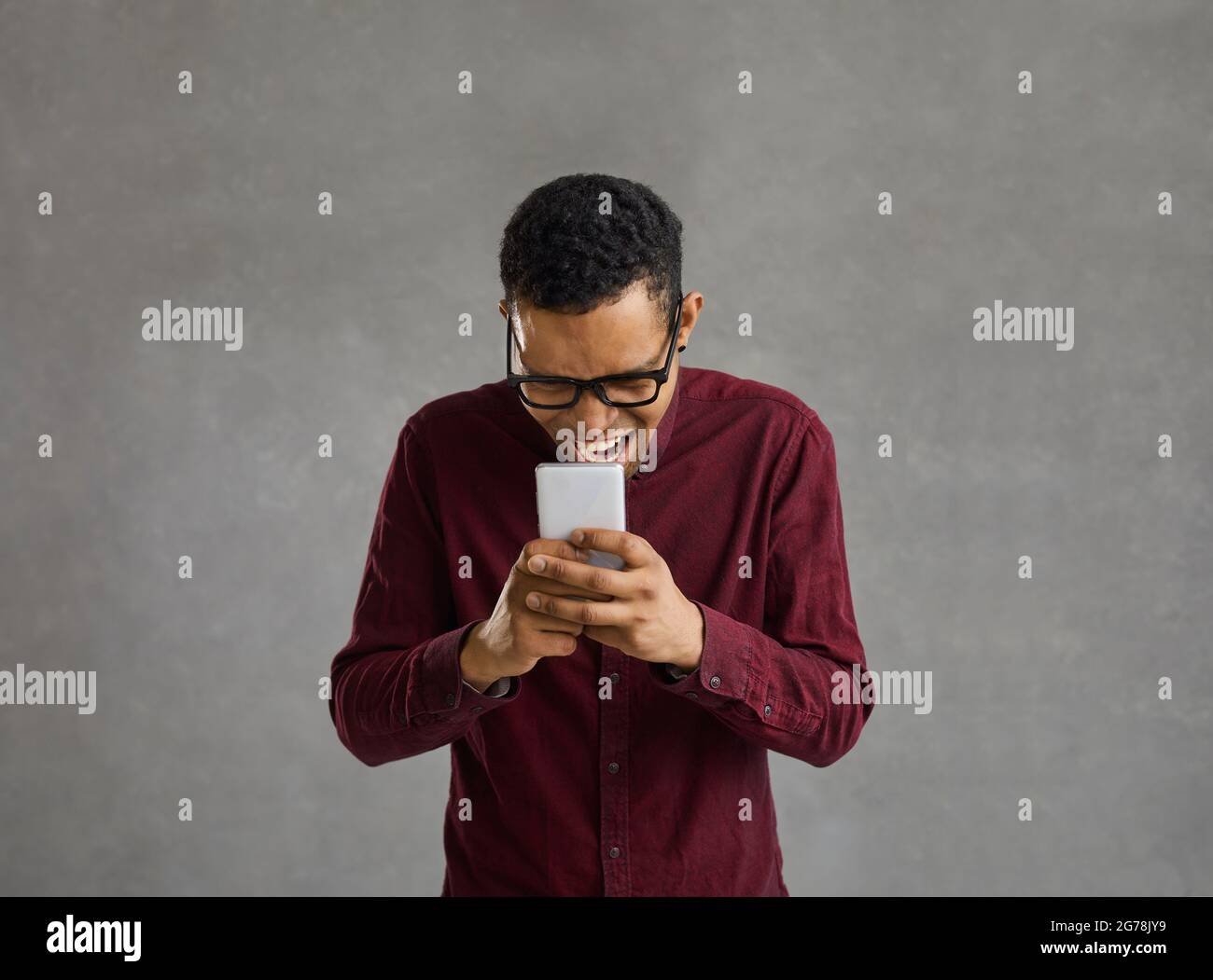 Black man holding mobile phone and laughing at funny memes and jokes on the Internet Stock Photo