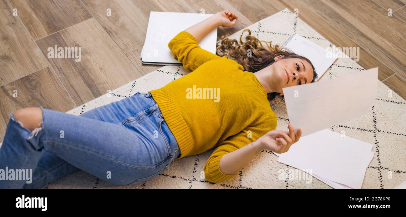 Young woman exhausted from work lying on the floor Stock Photo