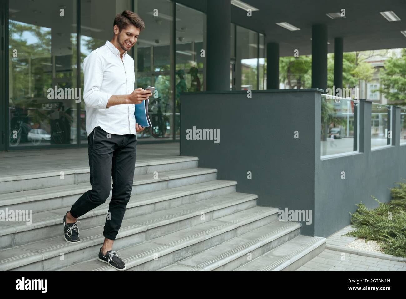 European businessman going on stairs and using mobile phone. Young man ...